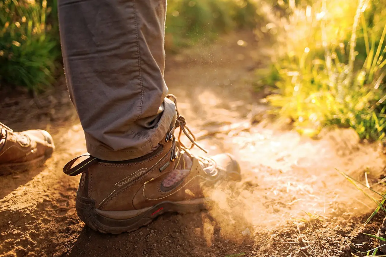 A hiking boot kicking up dust in golden light