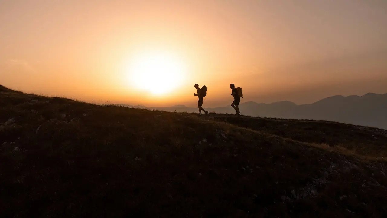 Two hikers on a hilltop at dusk